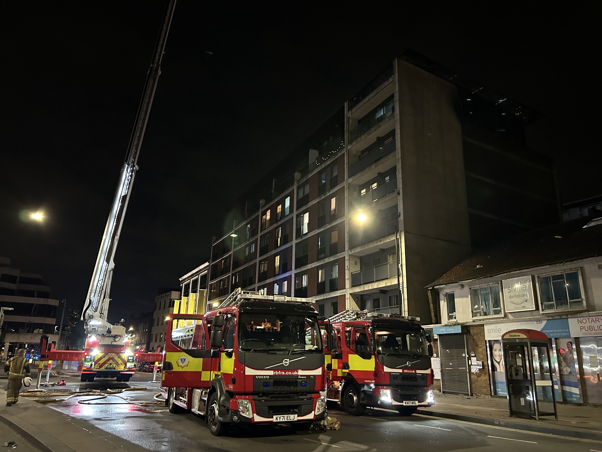 Three fire engines parked in front of an apartment block