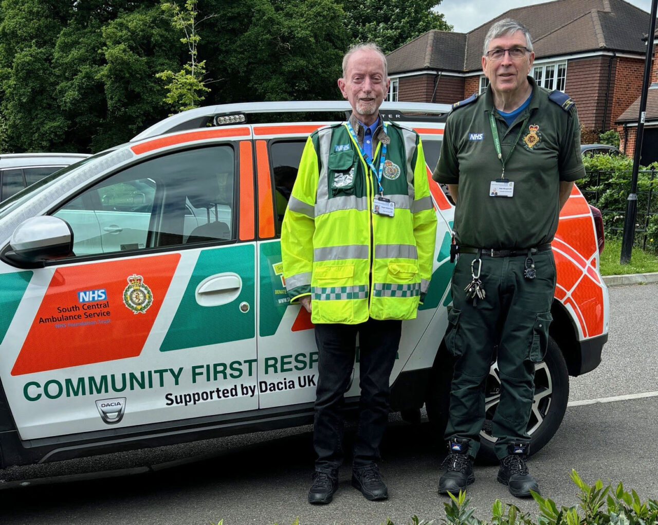 Volunteer responder and patient panel chair in front of car