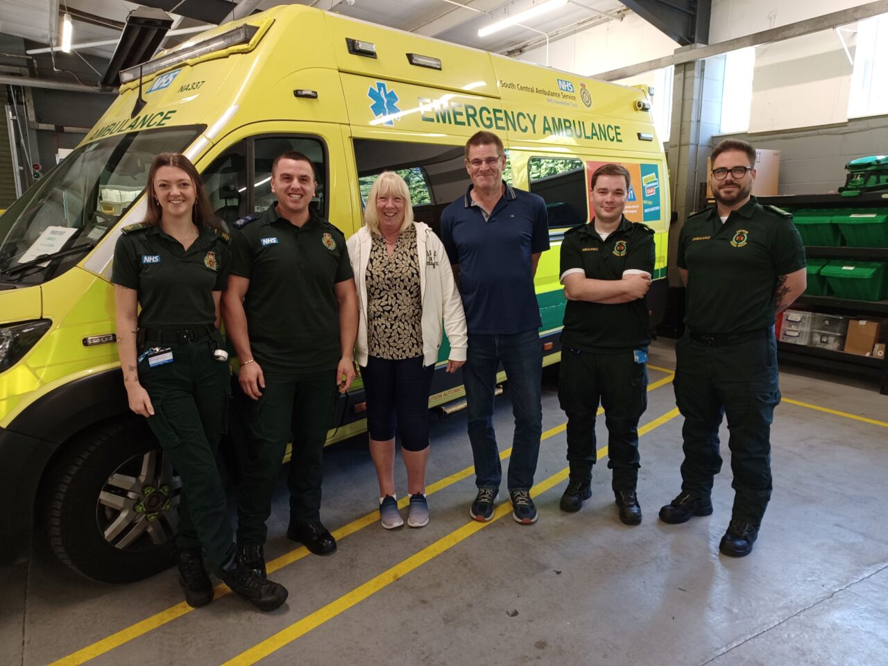 Paramedics with patient and her husband standing in front of an ambulance