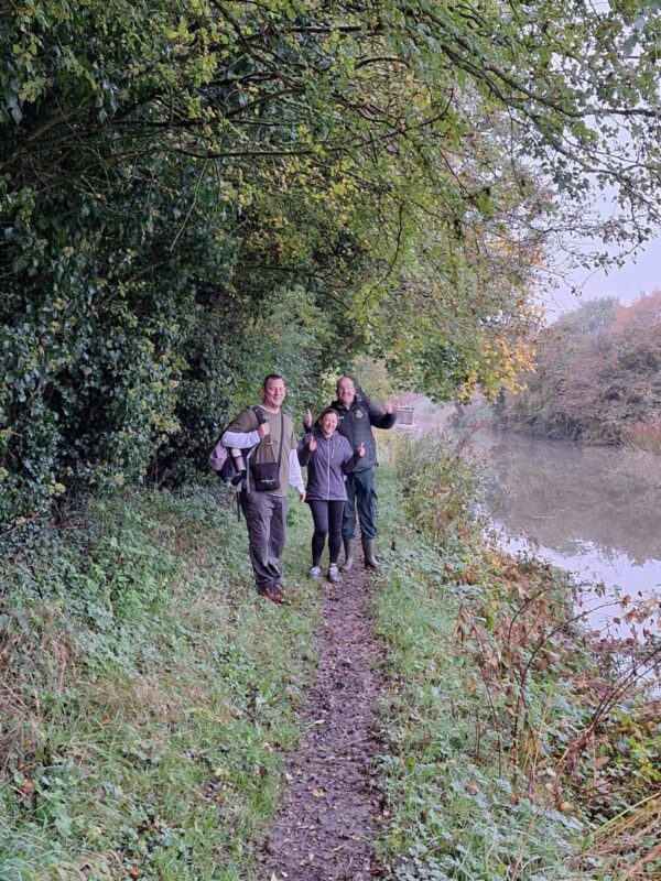 Two men and a woman walking next to a canal