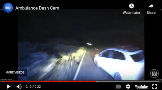 Still image from ambulance dash cam footage showing a white car driving at night