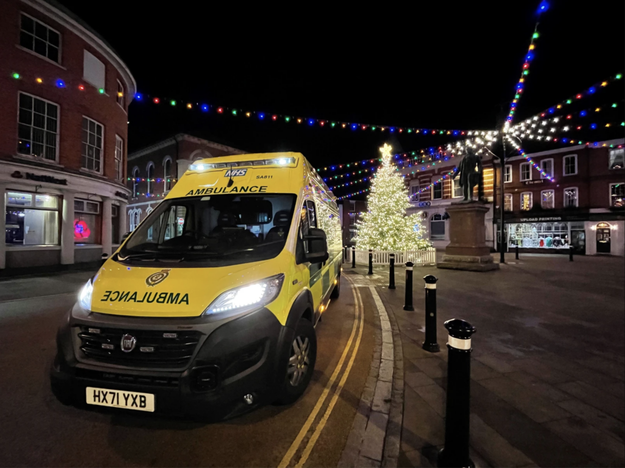 Ambulance parked in Romsey town centre in front of Christmas tree and Christmas lights