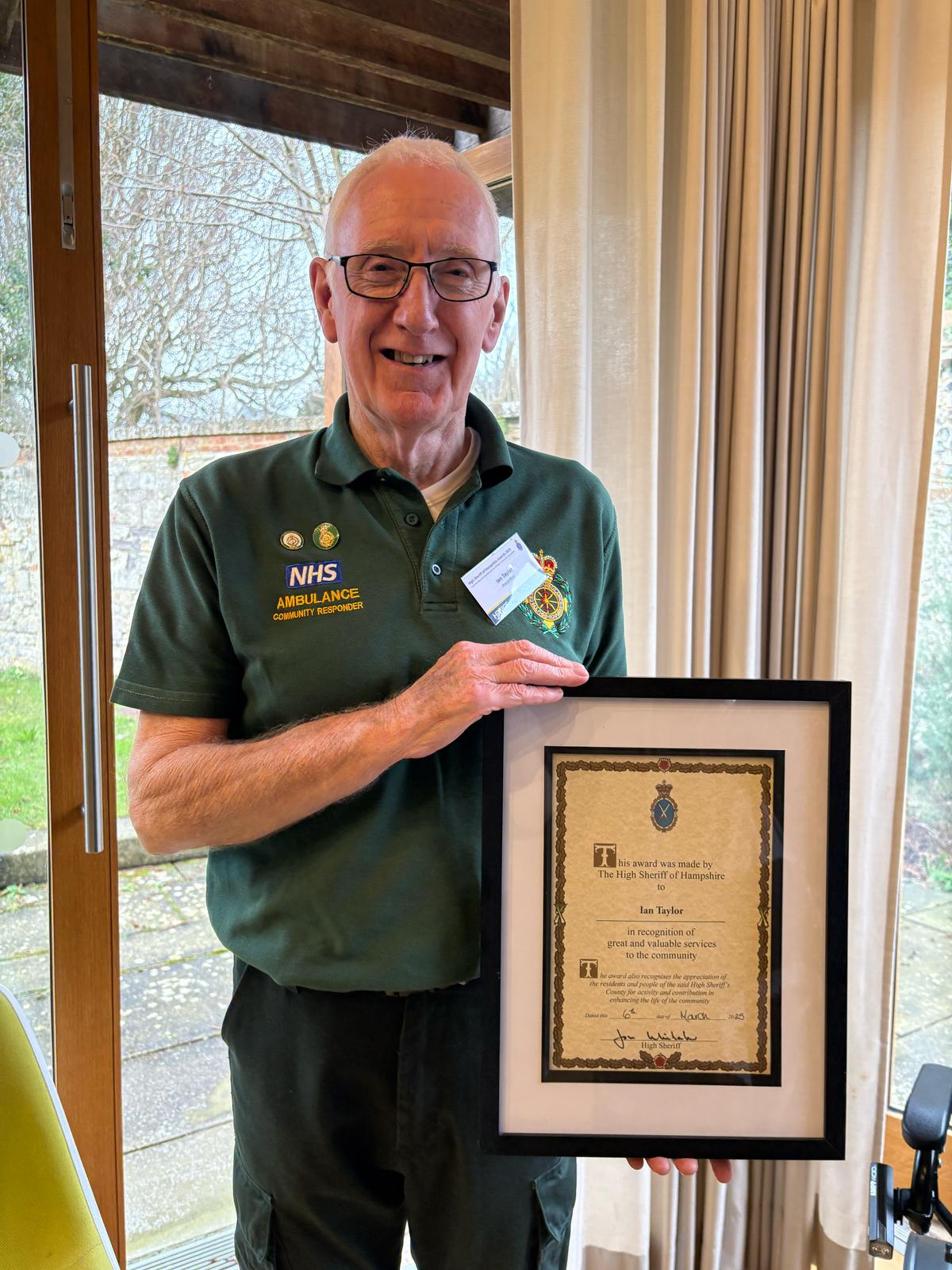 A community first responder holding a framed award certificate