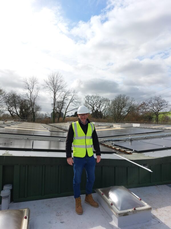 A man standing on a roof where solar panels are being installed